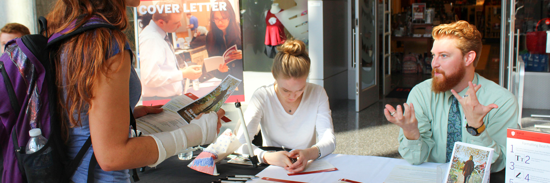 A student visiting a table in the Campus Center to discuss cover letters.